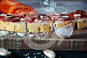 Slices of bread with ham, oil, tomato and garlic photo