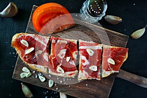 Slices of bread with ham, oil, tomato and garlic photo