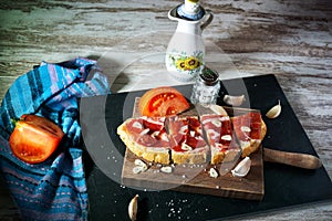 Slices of bread with ham, oil, tomato and garlic photo