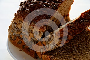 Slices of bread from several grains of sunflower and pumpkin and flax seeds in a white plate