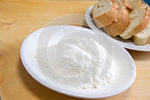 Slices of bread and wheat flour in a white plate on the table