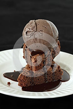 Slices of brownie covered with chocolate and chocolate ice crea