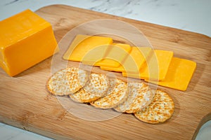 Slices of cheddar cheese and crackers on a cutting board