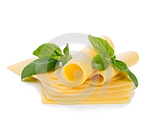 Slices of cheese with fresh basil leaves close-up isolated on a white background.