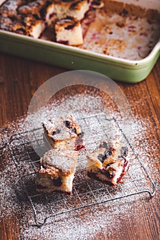 Slices of cherry cake on a cooling hatch with cake in a pan in a background.