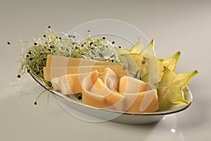 Slices of chhese with slices of starfruit and sprouts on the side