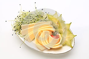 Slices of chhese with slices of starfruit and sprouts on the side