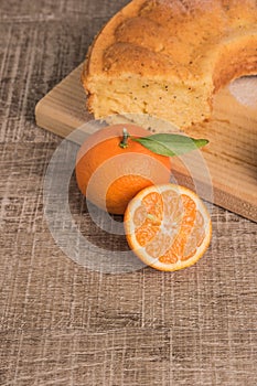 Slices of clementine cake with powdered sugar topping. Cake on a board with fresh clementines on wooden board