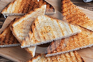 Slices of crispy bread toast for sandwiches on a cutting board, wooden rustic background. Close up