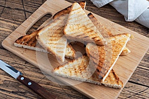 Slices of crispy bread toast for sandwiches on a cutting board, wooden rustic background. Close up