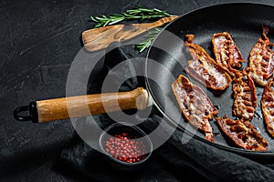 Slices of crispy hot fried cooked bacon. Farm organic meat. Black background. Top view