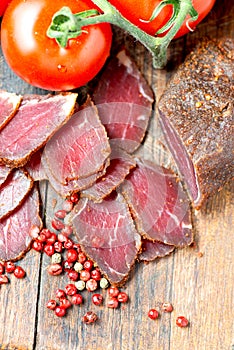Slices of cured meet on wooden table vertical