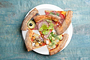 Slices of different delicious pizzas on blue table, top view