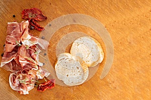 Slices of dried spanish ham with sun-dried tomatoes. Jamon Serrano on the wooden background.