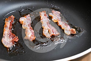 Slices of fresh fried bacon in a pan