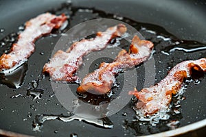 Slices of fresh fried bacon in a pan for breakfast