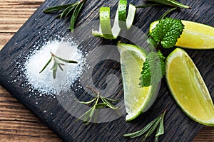 Slices of fresh lime, salt and rosemary on a wooden cutting Board