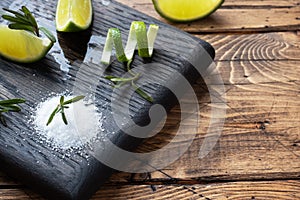 Slices of fresh lime, salt and rosemary on a wooden cutting Board