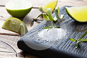 Slices of fresh lime, salt and rosemary on a wooden cutting Board