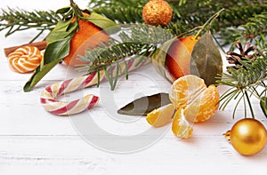 Slices of fresh peeled tangerine, lollipops, whole tangerines, spruce branches,  Golden Christmas ball on a white background
