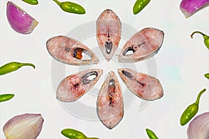 Slices of fresh tenualosa ilisha or hilsa fish with green chili pepper and sliced onion