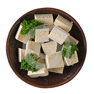 Slices of fresh tofu cheese in a clay bowl isolated on a white background. Soy cheese. Flat lay.