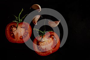 Slices of fresh tomatoes on black background with garlic