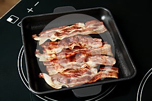 Slices of fried bacon on kitchen stove