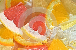 Slices of grapefruit, orange fruit and honey pomelo in water on white background. Pieces of grapefruit, orange fruit and