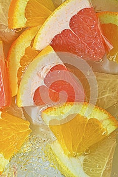 Slices of grapefruit, orange and pomelo in water on white background. Pieces of grapefruit, orange fruit and honey