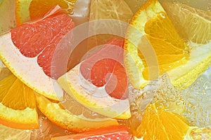 Slices of grapefruit, orange and pomelo in water on white background. Pieces of grapefruit, orange fruit and honey