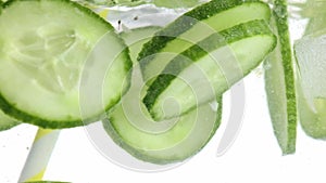 Slices of green juicy cucumber in water. Texture of cooling refreshing, detoxing summer's drink.