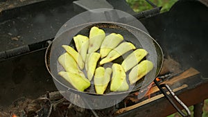 Slices of green pepper is frying on frying pan with oil in chargrill.