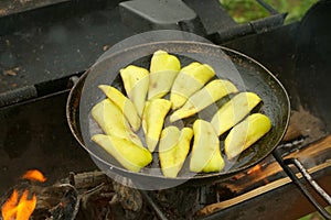 Slices of green pepper is frying on frying pan with oil in chargrill.