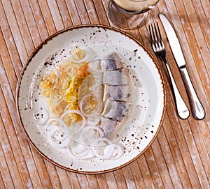 Slices herring fish with pickled cabbage, served on plate