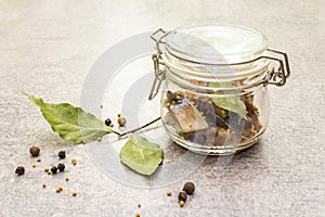 Slices of herring with spices in a glass jar