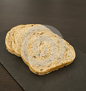 Slices of homemade multigrain bread on black slate board