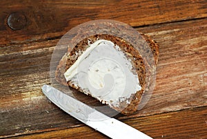 Slices of Homemade Whole Grain Bread with Butter and Knife over Wooden Background with Copy Space.