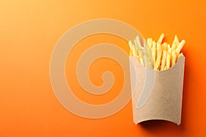 Slices of hot french fries in box on background, space for text. Top view