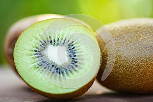 slices kiwi close up and fresh whole kiwi fruit wooden and nature green background