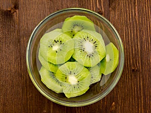 Slices of kiwi fruit on wooden bowl on top
