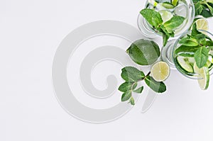 Slices lime, cucumber, leaves mint, ice and transparent cold drink on white wood plank, top view, copy space.