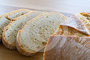 Slices and loaf of bread on wooden table.