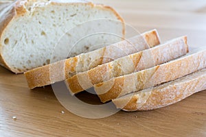 Slices and loaf of bread on wooden table.