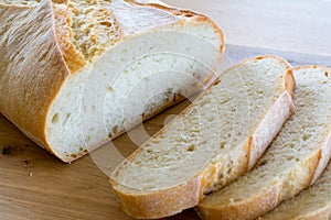 Slices and loaf of bread on wooden table.