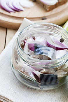 Slices of marinated mackerel with onion in a jar, lime, laurel and bread