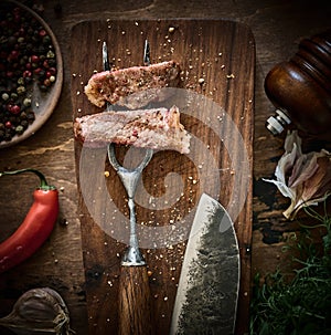 Slices of Medium rare grilled Steak Ribeye on meat fork on cutting board. Juicy piece of meat on a fork