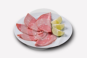 Slices of mortadella served with lemon .. top view
