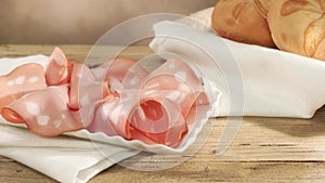 slices of mortadella on a white plate. italian sausage on a wooden table with bread. serving meat delicacy