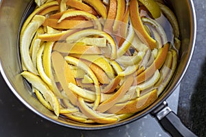 Slices of orange and lemon peels being cooked to make candied peels